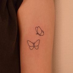 a woman's arm with two small butterflies on the left side of her arm