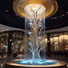 a water fountain in the middle of a room with glass walls and lights on it