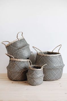 three black and white baskets sitting on top of a wooden table