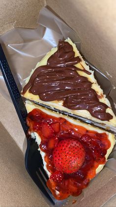 a piece of cake with chocolate frosting and strawberries on top in a box