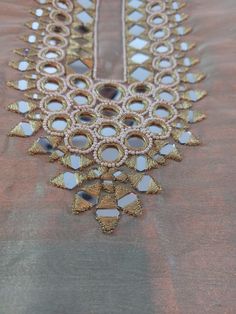 a gold and white beaded necklace is hanging from a piece of cloth on a table