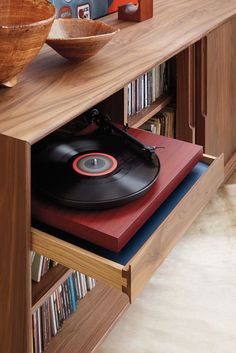 a record player sitting on top of a wooden shelf next to a bowl and bookshelf