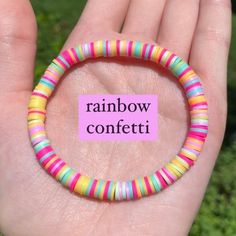 a hand holding a colorful bracelet with the words rainbow confetti written on it