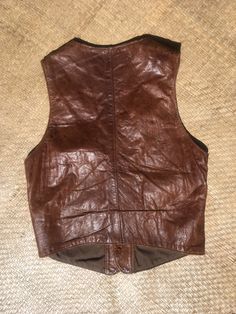 "Handcrafted Woodstock era leather vest. Rare artisan handmade piece. Buttery soft lightweight leather, feels like deerskin. Good for watmer weather or wearing as a sleeveless top. Buffalo nickel buttons, appear to be either real silver or pewter- they have a copper shank. Unmarked and untested, but they are made out of real coins- I can see on the back 1930s hallmarks and a caricature profile of an Indigenous person. Cotton lining. Very good to good vintage condition. Worn and distressed with c Brown Biker Vest, Fitted Western Leather Vest, Black Leather Vest Vintage, Vintage Brown Vest With Button Closure, Vintage Western Leather Vest, Buffalo Nickel, Deer Skin, Leather Vest, Woodstock