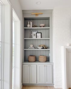 a white book shelf with baskets and books on it