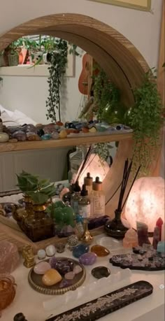 a table topped with lots of different types of items next to a mirror and potted plant