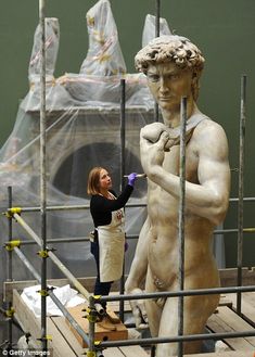 a woman standing next to a statue in front of scaffolding