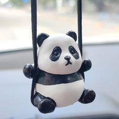 a panda bear toy hanging from the side of a car window in front of a windshield