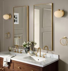 a bathroom with two sinks, mirrors and gold faucets on the wall above them