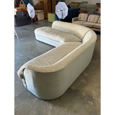 a large couch sitting on top of a cement floor next to other furniture in a room