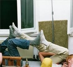 two people laying on the ground in front of a window with one person upside down