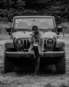 a woman sitting on the hood of a jeep