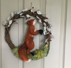 a wreath with a red fox hanging from it's side