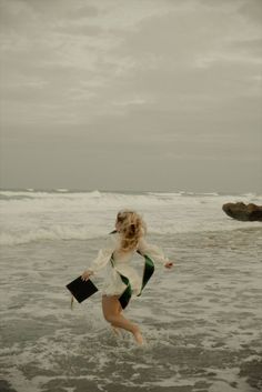 a woman is running in the water at the beach