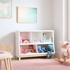 a toy horse sitting on top of a wooden floor next to a white book shelf