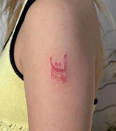 a woman's arm with a small tattoo of a cat on the left shoulder