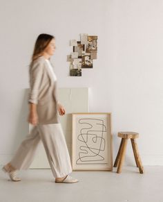 a woman walking past an art piece on the floor next to a stool and table