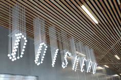 the lights are hanging from the ceiling in the building's lobby, which is decorated with wood slats