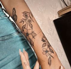 a woman's arm with flowers and butterflies tattooed on the left side of her arm