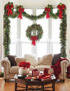 a living room decorated for christmas with wreaths and poinsettis on the windowsill