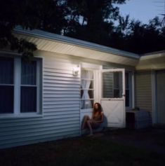 a woman sitting on the porch of a house at night