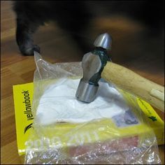 a hammer and plastic bag on the floor next to an animal's paw that is sticking out of it