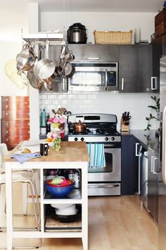 a kitchen with stainless steel appliances and wooden flooring is pictured in this image, there are pots hanging from the ceiling