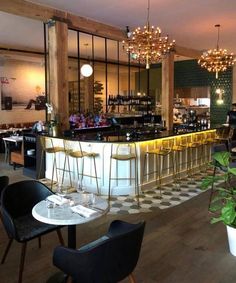 an empty restaurant with tables and chairs in front of the bar, along with potted plants