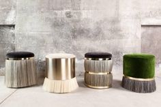 three stools with different colors and designs in front of a concrete wall on the floor