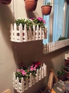 three hanging planters with flowers in them on the side of a wall next to a window