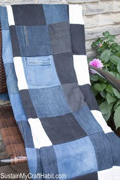 a blue and black blanket sitting on top of a chair next to a potted plant