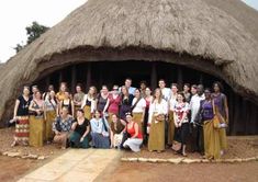 a group of people standing in front of a hut