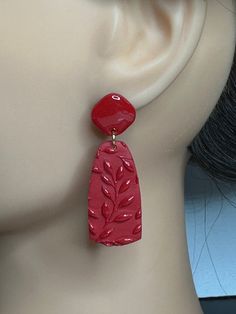 a pair of red earrings on top of a mannequin's dummy head