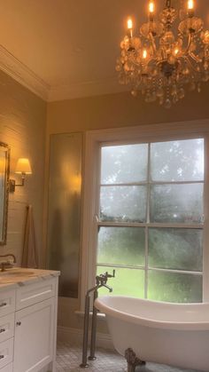 a bath room with a tub and a chandelier hanging from it's ceiling