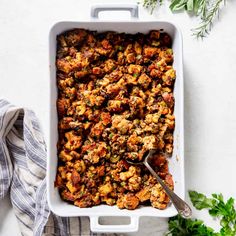 a casserole dish filled with stuffing and topped with parsley on the side