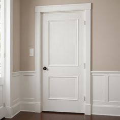 an empty room with a white door and wooden floors