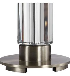 a glass and metal table lamp sitting on top of a silver plate with a circular base