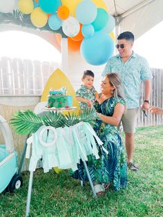 a man and woman standing next to a baby carriage under a canopy with balloons on it