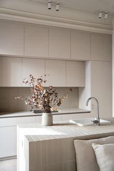 a vase filled with flowers sitting on top of a kitchen counter next to a sink