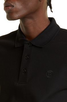 An embroidered emblem featuring founder Thomas Burberry's interlocking initials details this soft cotton-jersey polo. 28 1/2" length Button half-placket Johnny collar Short sleeves 100% cotton Machine wash, dry flat Imported Men's Designer Clothing Designer Black Polo Shirt With Embroidered Logo, Classic Polo Shirt With Embroidered Logo For Work, Classic Collared Tops With Logo Detail, Classic Polo Shirt With Logo Detail, Classic Collared Polo Shirt With Logo Detail, Classic Black Polo Shirt For Business, Classic Black Business Polo Shirt, Johnny Collar, Half Sleeve Shirts