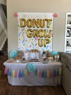 a table topped with donuts and cake next to a sign that says donut grow up