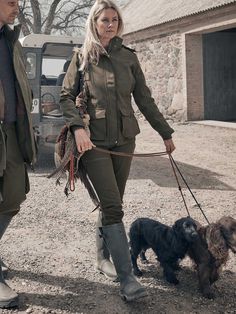 a man and woman walking two dogs in the dirt