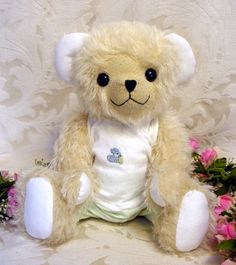 a stuffed teddy bear sitting next to some flowers