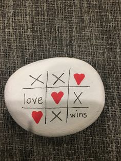 a white rock with red hearts and crosses on it that says love, loves, wins