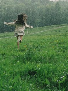 a girl running in the rain with her arms outstretched