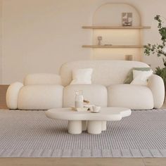 a modern living room with white furniture and plants in the corner on the side table