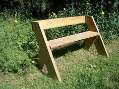 a wooden bench sitting on top of a lush green field next to tall grass and yellow flowers