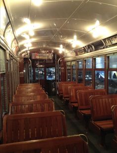 the inside of a train car with wooden seats and lights on it's ceiling