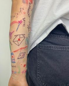 a woman's arm with colorful tattoos on it and writing all over the arm