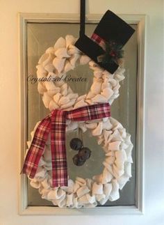 a white wreath with red and black bows hanging on a door